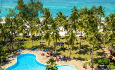 A picturesque beach with a swimming pool surrounded by lush palm trees, offering a tropical getaway.