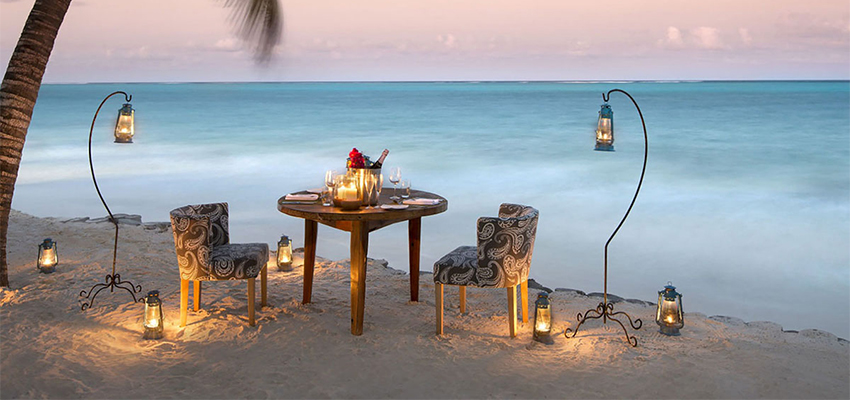 Two chairs and a table surrounded by beautiful lights set up on the beach, creating a cozy and inviting atmosphere.