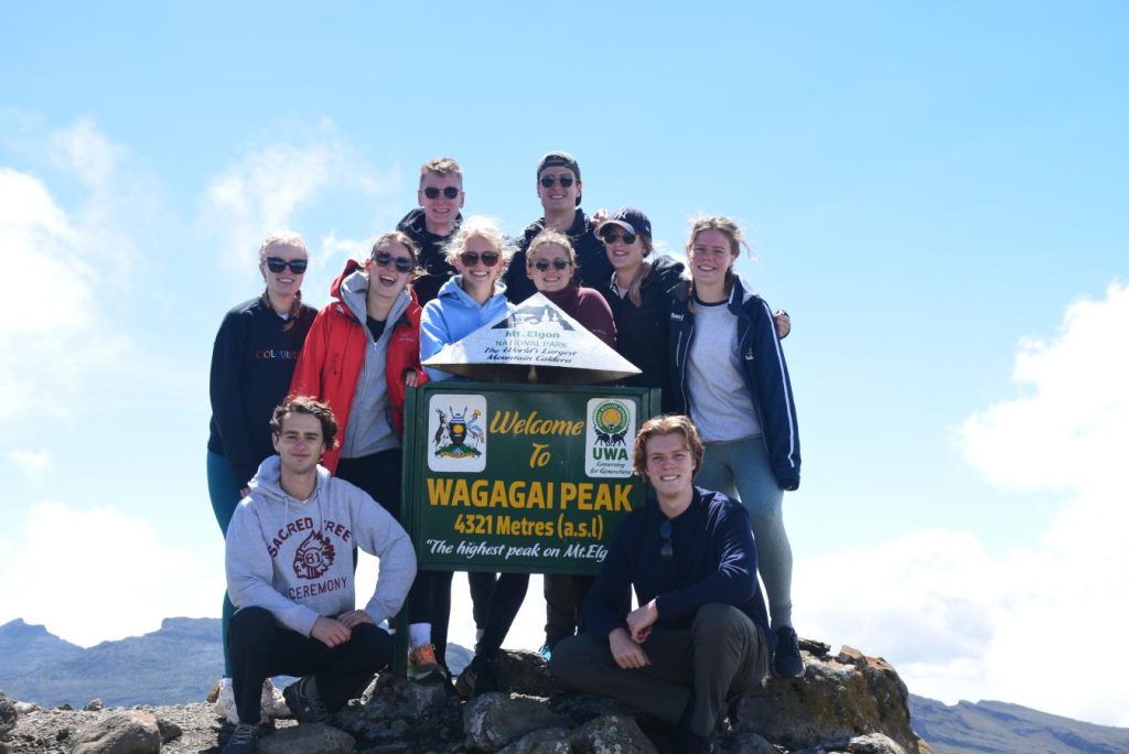 Tourists standing triumphantly at the summit of Wagagai Peak, Mount Elgon, at 4,321 meters.