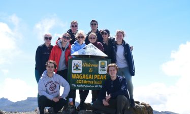Tourists standing triumphantly at the summit of Wagagai Peak, Mount Elgon, at 4,321 meters.