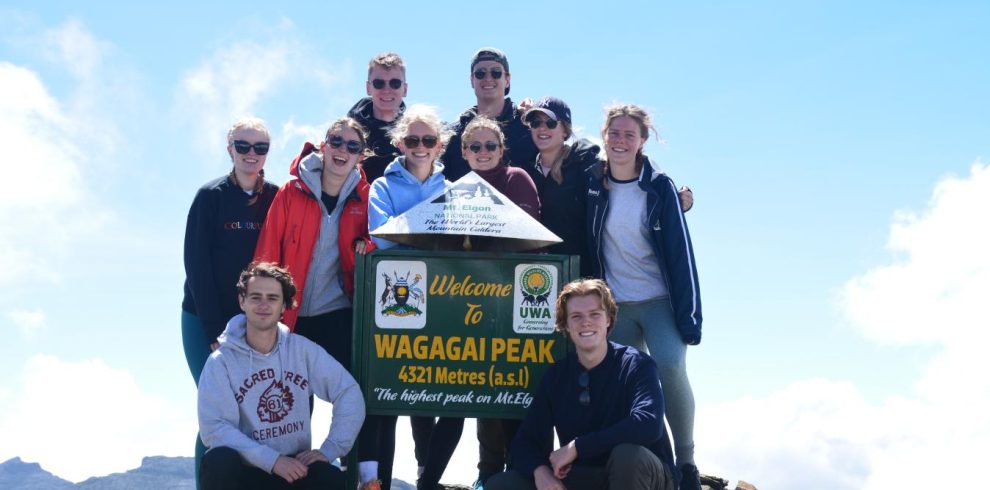 Tourists standing triumphantly at the summit of Wagagai Peak, Mount Elgon, at 4,321 meters.