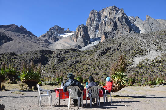 A tourist seated on a plastic chair on a mountain, taking a rest and enjoying the view.