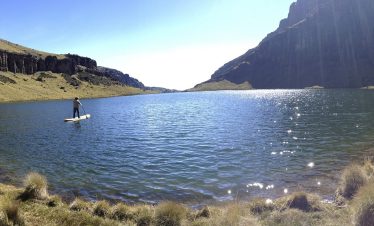 A serene water body on Mount Kenya, surrounded by rocky terrain and high-altitude landscape.