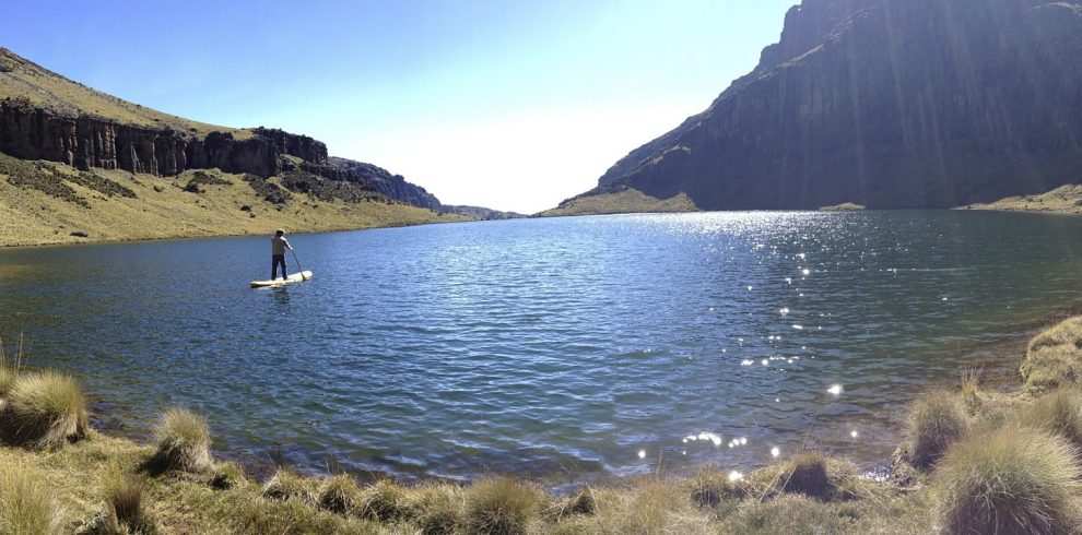 A serene water body on Mount Kenya, surrounded by rocky terrain and high-altitude landscape.