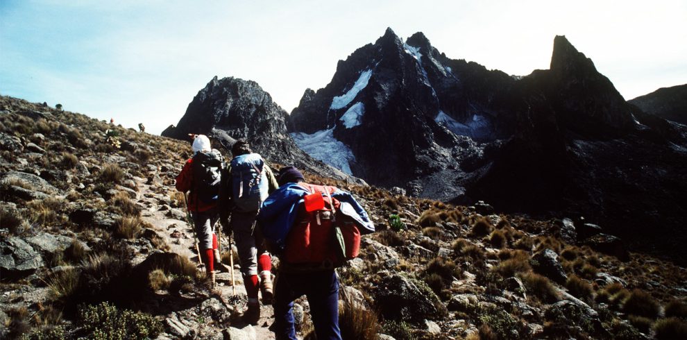 wo tourists climbing Mount Kenya with the assistance of one guide, navigating rocky terrain.