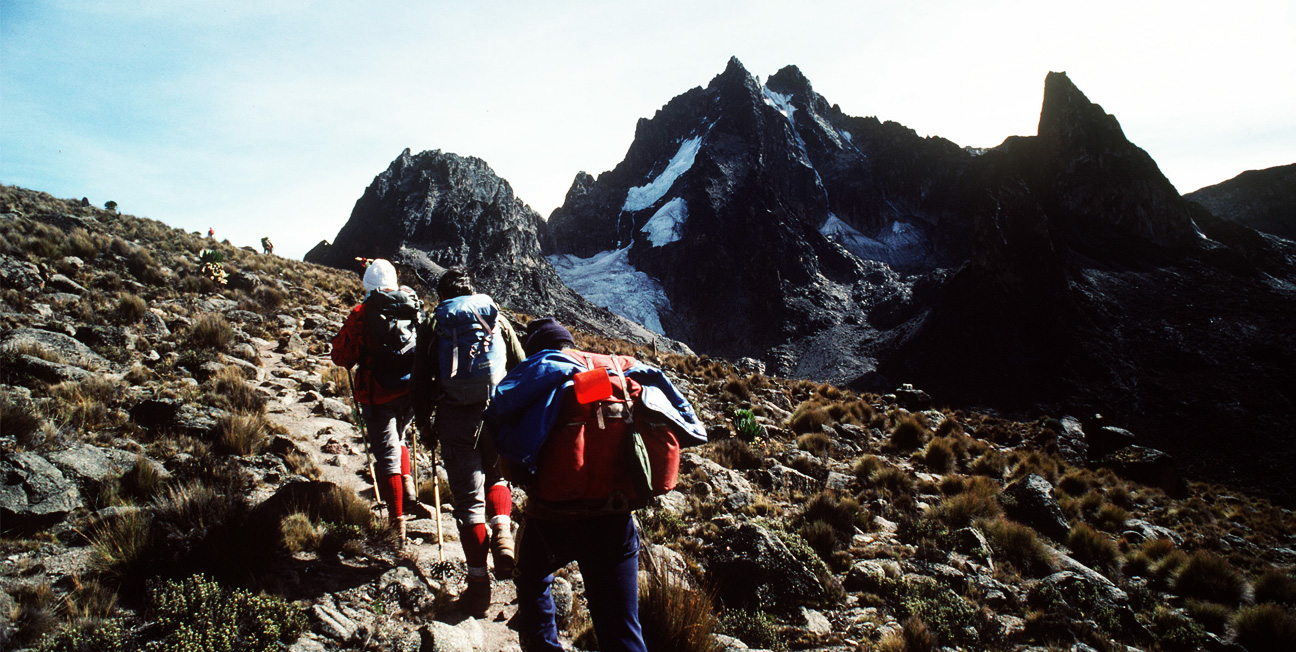 wo tourists climbing Mount Kenya with the assistance of one guide, navigating rocky terrain.