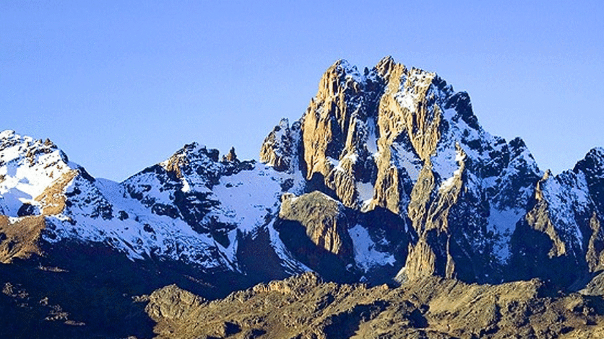 The high point of Mount Kenya, showcasing the rugged, snowy summit against a clear blue sky.