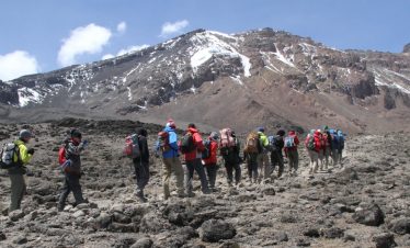Hikers ascending the steep Umbwe Route on Mount Kilimanjaro during a 7-day climb, surrounded by dense forests and rugged terrain.